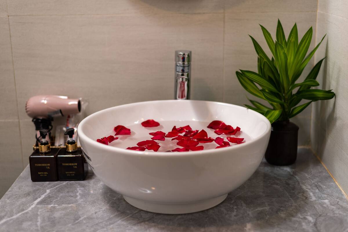 Ein Badezimmerwaschbecken mit Rosenblüten, einem Fön und zwei Toilettenartikeln.
