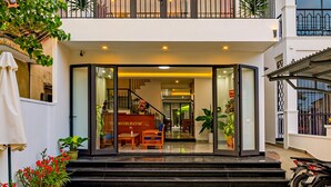 A multi-story hotel with a central entrance, balconies on each floor, and a covered outdoor area with potted plants. - Tomorrow Villa Hoi An (Da Nang)