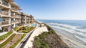 A beachfront hotel with multiple balconies, a pool, and a sandy beach. - Steps to Sand, Luxury Family Townhome with Central A/C BBQ Crib Resort Amenities (Solana Beach)