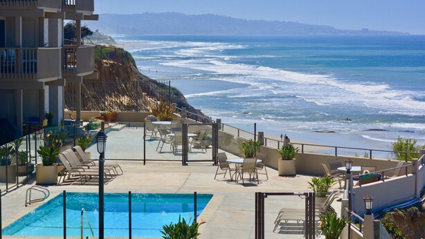 A rooftop pool with lounge chairs and a view of the ocean. - Steps to Sand, Luxury Family Townhome with Central A/C BBQ Crib Resort Amenities (Solana Beach)