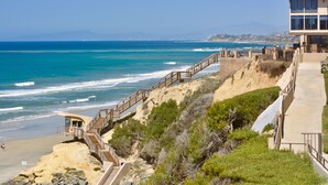 A coastal hotel with a wooden staircase leading to a beach area, a view of the ocean, and a clear sky. - Steps to Sand, Luxury Family Townhome with Central A/C BBQ Crib Resort Amenities (Solana Beach)
