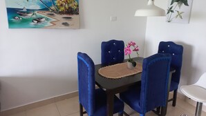 Un comedor con mesa, sillas y un cuadro de una escena de playa.
