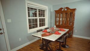 Un comedor con una mesa blanca, individuales rojos y un mueble de madera.