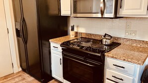Een keuken met een zwarte koelkast, een roestvrijstalen magnetron en een fornuis.