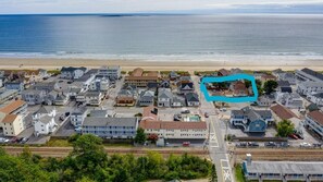 Une vue aérienne d’une ville côtière, avec un mélange de bâtiments résidentiels et commerciaux, une plage en arrière-plan et une voie ferrée qui traverse le centre-ville.