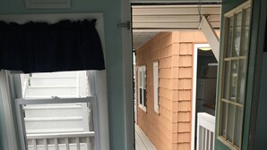 Una camera da letto con finestra, porta e vista su un'area esterna in legno.