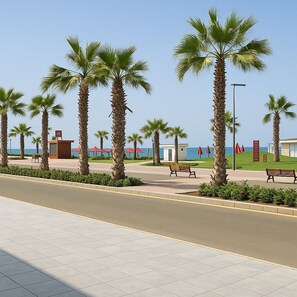 A coastal promenade with palm trees, benches, and a small kiosk.