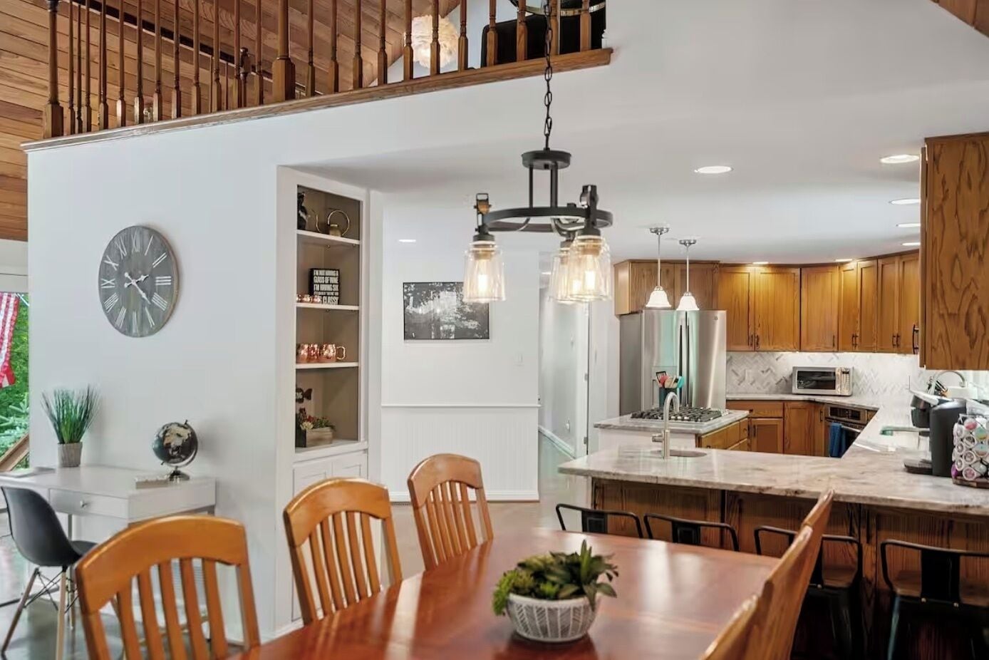 A modern kitchen with wooden cabinets, a central island, and pendant lighting.