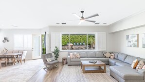 A spacious living room with a grey sectional sofa, a coffee table, and a dining area with a table and chairs. - NEW: Pool, Spa, Tiki Bar, Mini Golf, Firepit, Desert Views (Desert Hot Springs)