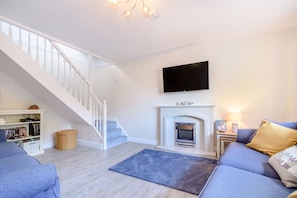 Una sala de estar moderna con una escalera, una chimenea, un televisor de pantalla plana y un sofá.