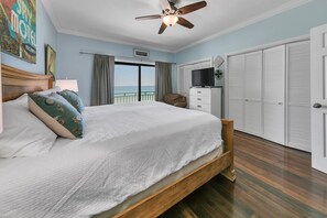 Ein Schlafzimmer mit Bett, Deckenventilator, Fernseher, Kleiderschrank und Meerblick.