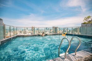 A rooftop infinity pool with a city skyline view, a glass railing, and a clear sky. - The Dream Suite (Da Nang)