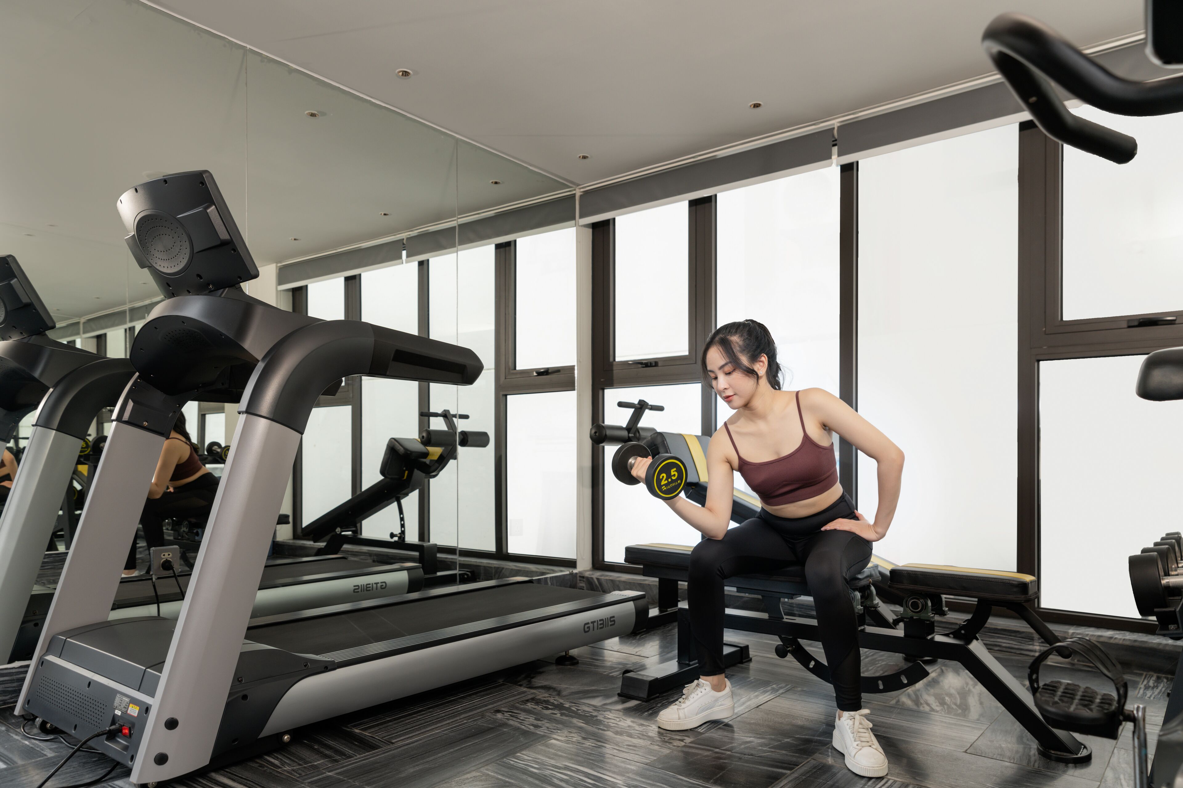 Uma academia com esteiras, aparelhos de musculação e um grande espelho.