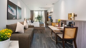 A modern hotel room with a sofa, a dining area, a TV, and a large window. - The Dream Suite (Da Nang)