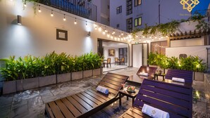A rooftop lounge area with wooden loungers, string lights, and potted plants. - The Dream Suite (Da Nang)