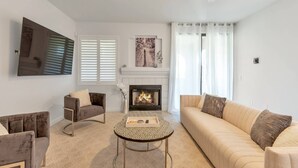 Ein Wohnzimmer mit Kamin, zwei Sofas, einem Couchtisch und einem an der Wand montierten Fernseher.
