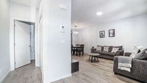 Un salon moderne avec un canapé gris, une table à manger avec des chaises et un lustre.