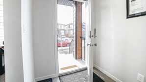 Une entrée moderne avec une porte en verre, un cadre de porte en bois et un portail en métal.