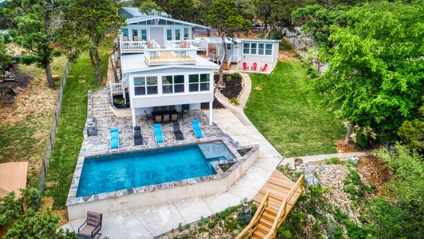 Una casa grande con piscina, mobiliario exterior y terraza.