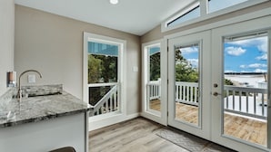 Una cocina moderna con encimera de granito, pileta integrada y vista a una terraza de madera y espacio exterior.