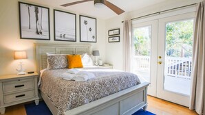 Una camera da letto con un letto, comodini, una ventola a soffitto e vista all'esterno tramite una porta scorrevole.