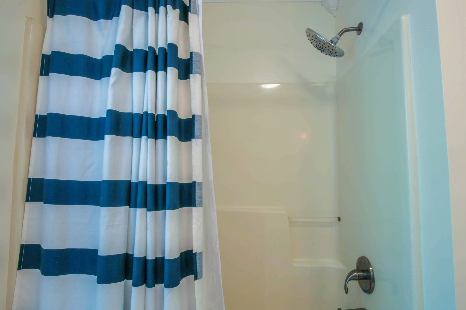 A bathroom with a shower, a curtain, and a bathtub.