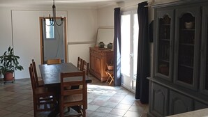 A dining area with a table and chairs, a cabinet, and a potted plant. - VILLA VAUNAGE (Calvisson)