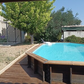 A wooden deck surrounding a rectangular swimming pool with a wooden deck edge.
