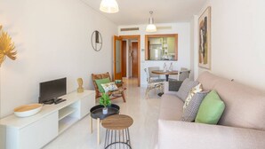 Ein modernes Wohnzimmer mit einer Couch, einem Fernseher und einem Essbereich mit Stühlen und einem Tisch.