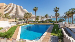 Ein Hotel mit einem großen Schwimmbad, Palmen und Meerblick.