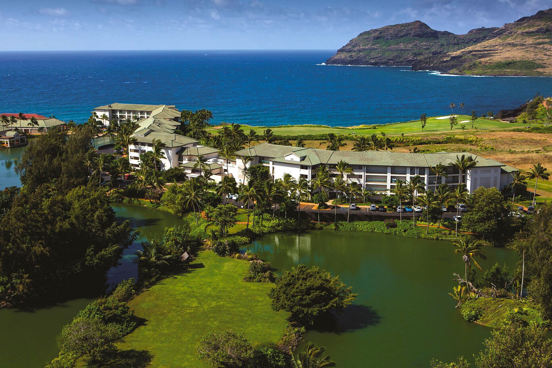 A resort with multiple buildings, a golf course, and a body of water.