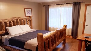 Ein hölzernes Bett mit Kopfteil, ein Nachttisch und ein Sessel.