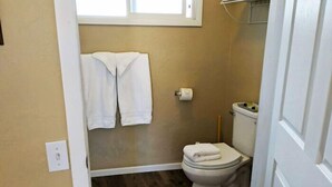 Ein kleines Badezimmer mit Toilette, Handtuchhalter und einer Toilettenpapierrolle.