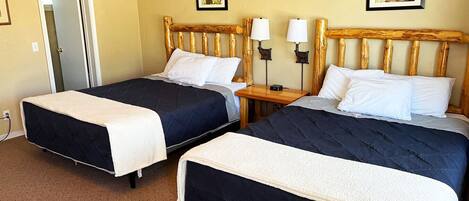 A hotel room with two beds, a wooden headboard, bedside lamps, and two framed pictures on the walls.