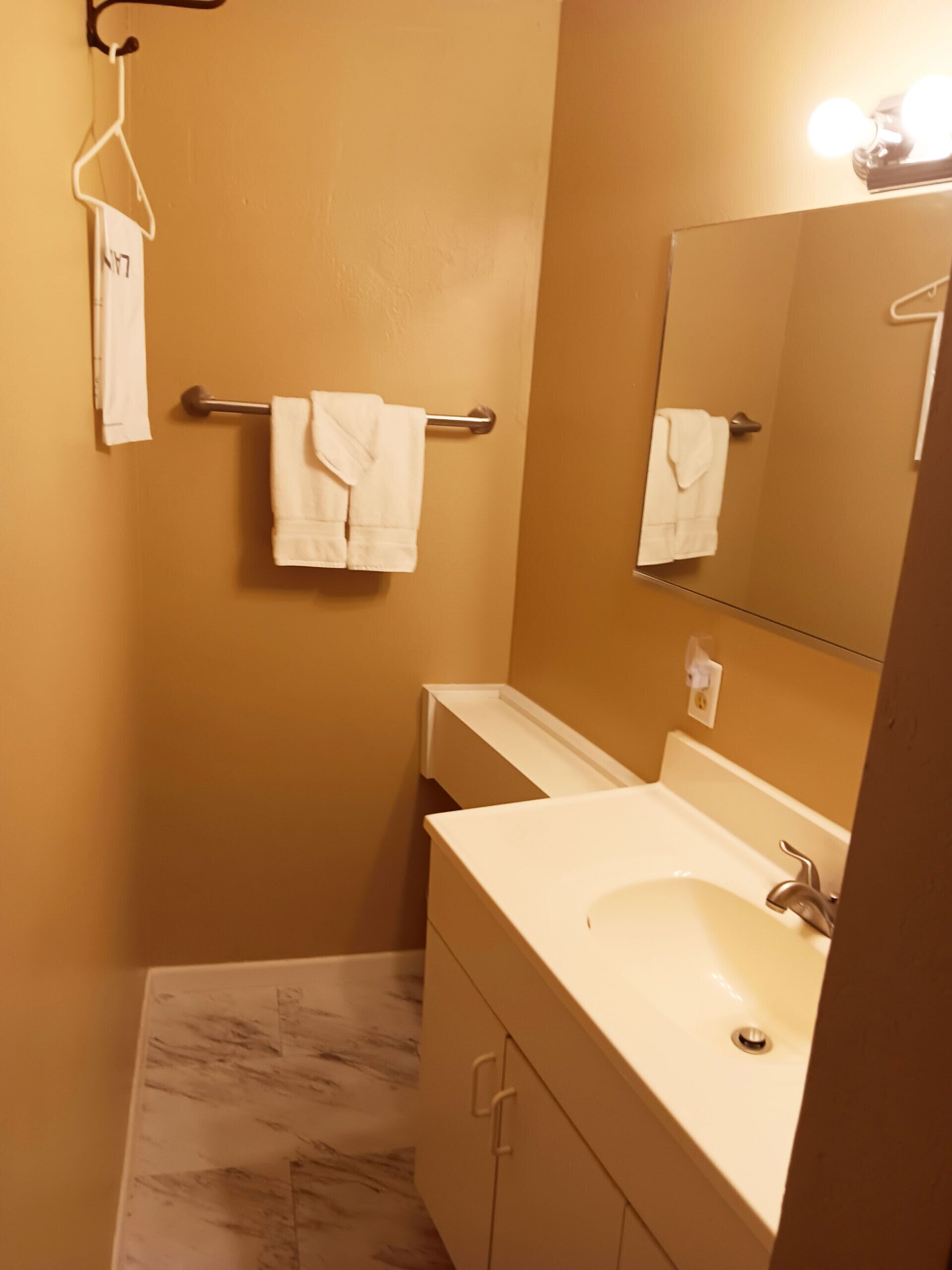 Ein Badezimmer mit Waschbecken, Spiegel, Handtuchhalter und Marmorboden.