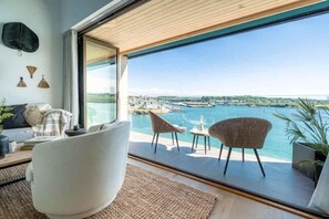 Ein modernes Zimmer mit großem Fenster und Blick auf einen Hafen und das Wasser.