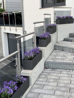 A staircase with metal railings and planters with purple flowers.