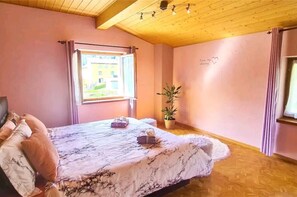 A bedroom with a bed, a window, a potted plant, and a wall with a heart-shaped decoration. - Cozy little apartment with whirlpool a few min from the center of Poschiavo (Poschiavo)