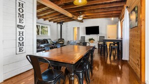 A spacious dining area with a wooden table and chairs, a ceiling fan, and pendant lights.