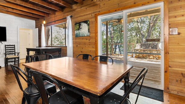 A wooden interior with a large dining table, chairs, and a painting of a horse.