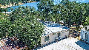 A single-story RV with a flat roof, surrounded by trees and a lake view.