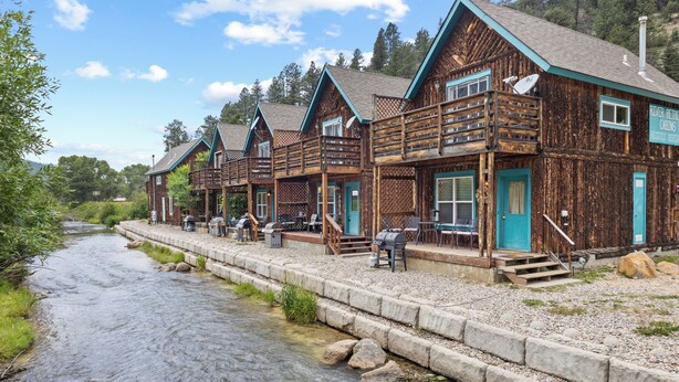 Une rangée de cabanes en bois, avec une rivière en contrebas.