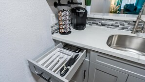 Une cuisine équipée d’un lave-vaisselle encastré, d’une machine à café et d’un tiroir pour ranger les couteaux.