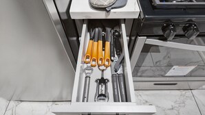 Un tiroir de cuisine contenant divers ustensiles, notamment un marteau, une pince et un décapsuleur.