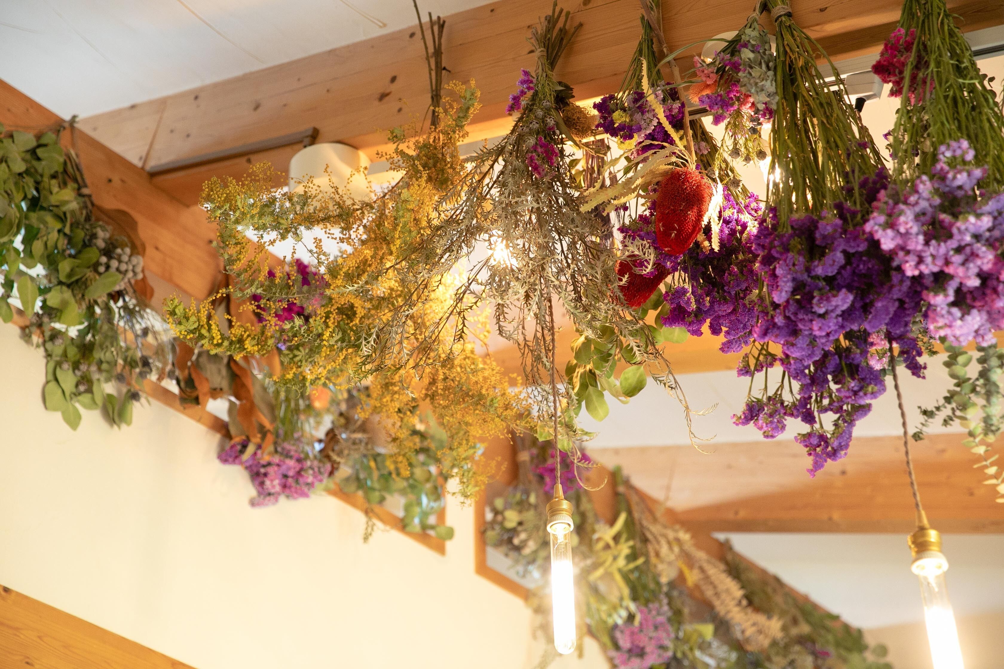 A ceiling with wooden beams and hanging floral arrangements.
