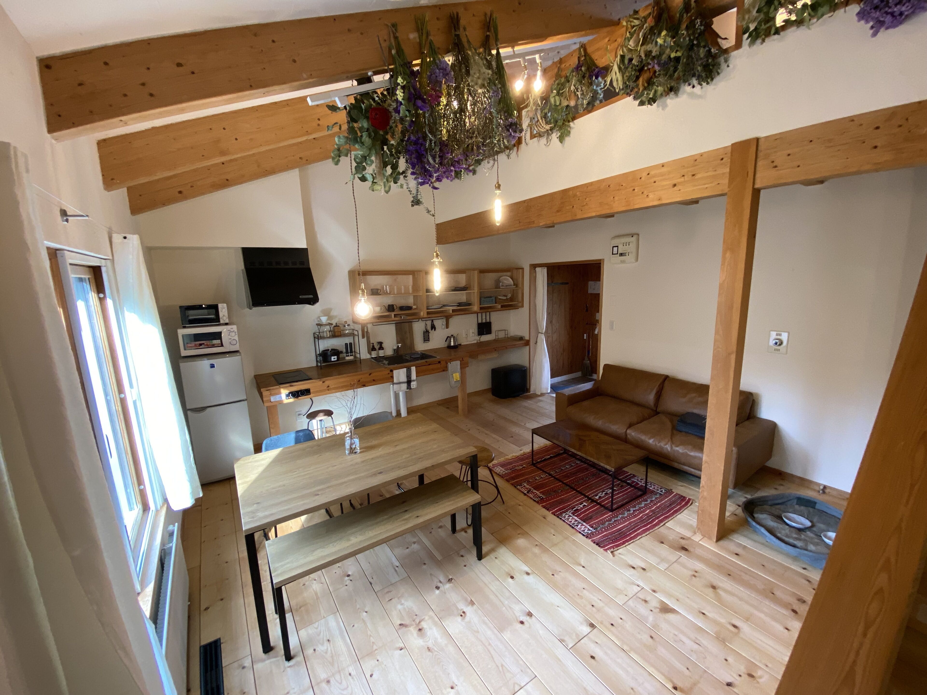 A compact kitchen with wooden beams, a dining table, and a sofa in a living area.