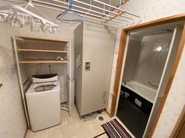 Un baño pequeño con lavadora, inodoro y zona de ducha.