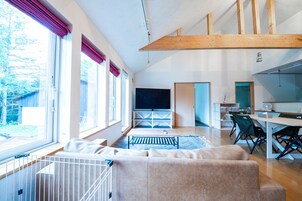 Amplia sala de estar con un ventanal grande, televisor y comedor con mesa y sillas.
