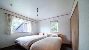 A bedroom with two beds, a wardrobe, and two windows. - THE FAM (Nakafurano)