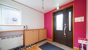 A room with a wooden cabinet, a black door, and a fire extinguisher sign. - THE FAM (Nakafurano)